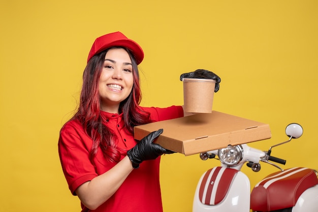 Free Photo front view of female courier with food box on a yellow wall