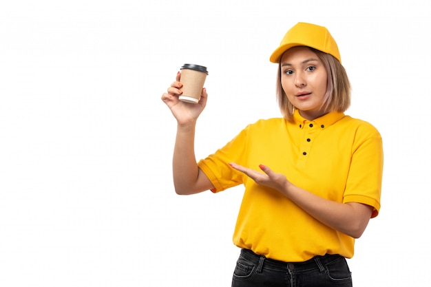 A front view female courier in yellow shirt yellow cap and black jeans holding coffee cup on white