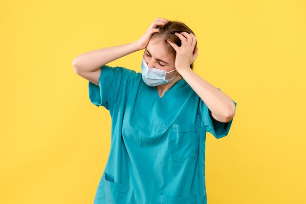 Front view female doctor having headache on yellow background covid- hospital health pandemic