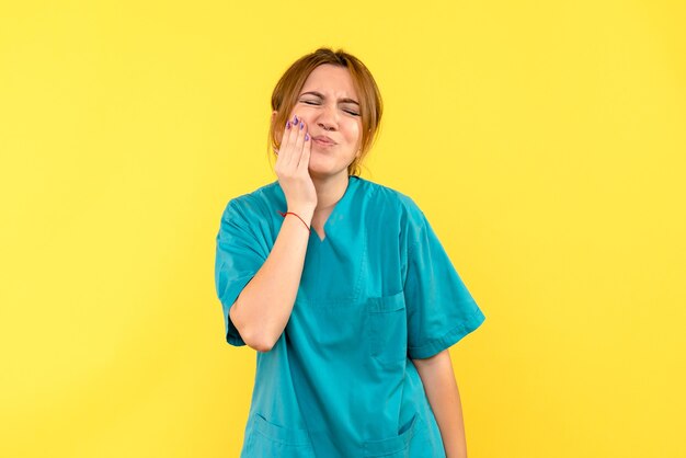 Front view female doctor having toothache on yellow space