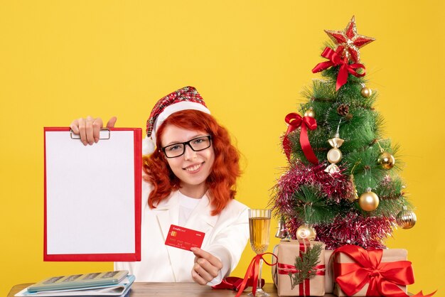 Front view female doctor holding bank card and note