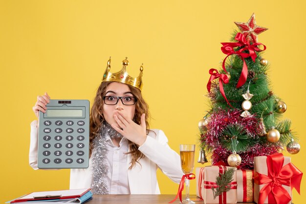 Free photo front view female doctor holding calculator with crown