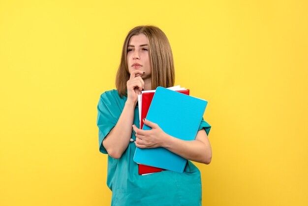 Front view female doctor holding documents on the yellow space