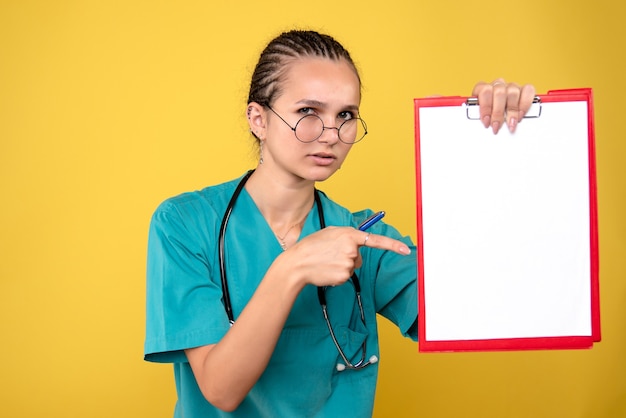 Free photo front view female doctor holding medical clipboard and pen, color nurse hospital emotions covid-19 medic health