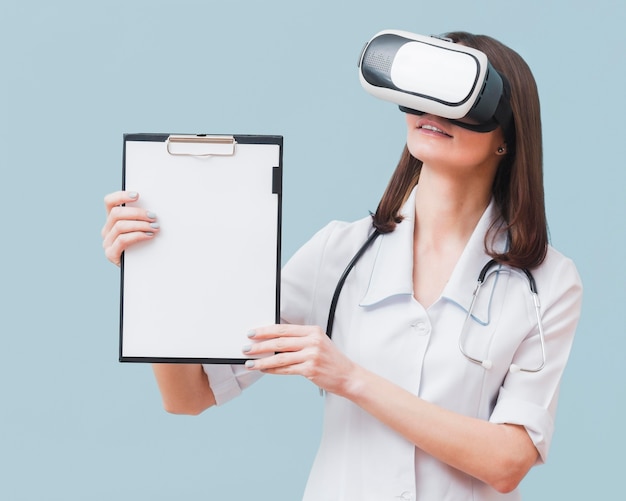 Free Photo front view of female doctor holding notepad while wearing virtual reality headset