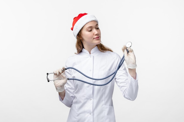 Front view of female doctor holding stethoscope on white wall