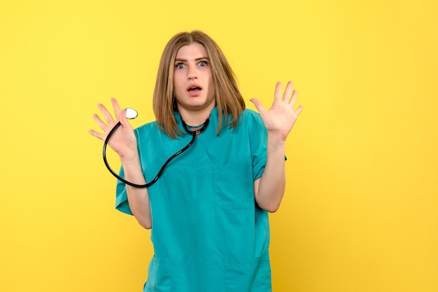 Front view female doctor holding tonometer on yellow floor hospital medical emotion