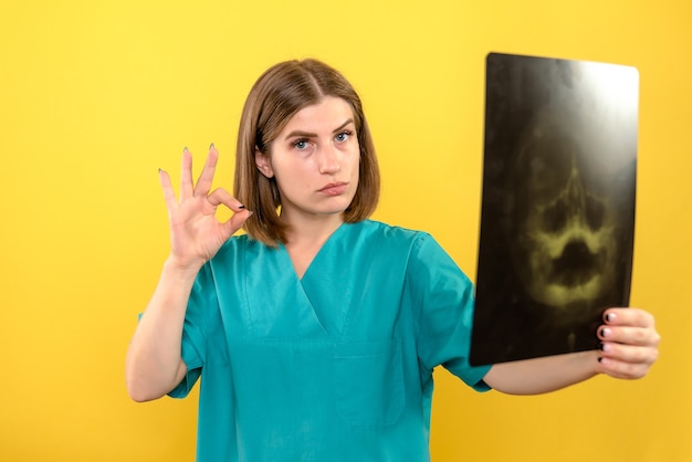 Free photo front view female doctor holding x-ray on yellow space