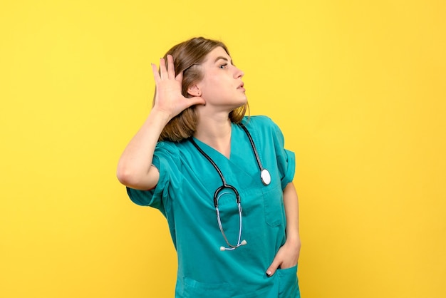 Free photo front view female doctor listening on yellow space