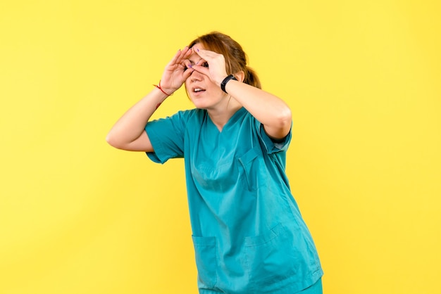 Front view female doctor looking through fingers on yellow space