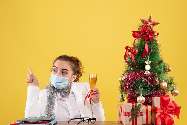 Front view female doctor in mask celebrating xmas with champagne