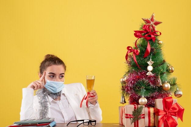 Front view female doctor in mask celebrating xmas with champagne