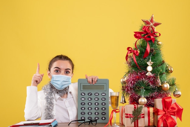 Free photo front view female doctor in mask holding calculator