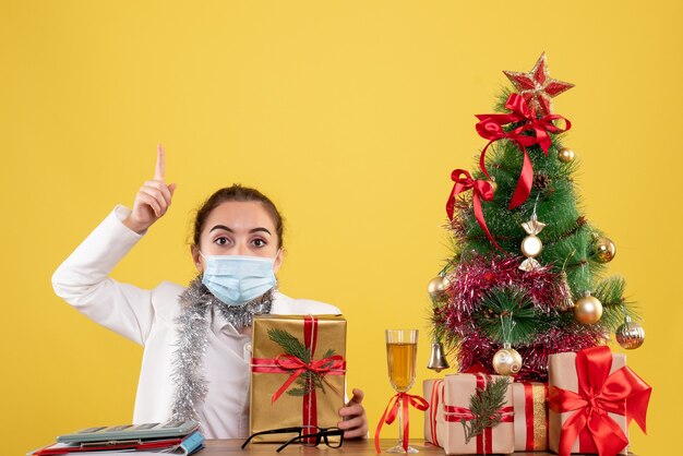 Front view female doctor in mask holding present