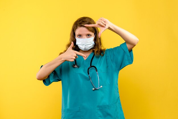 Front view female doctor in mask on the yellow space