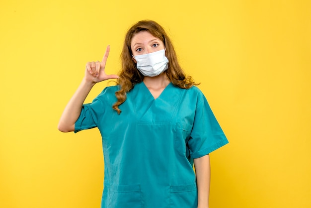 Free photo front view female doctor in mask on yellow space