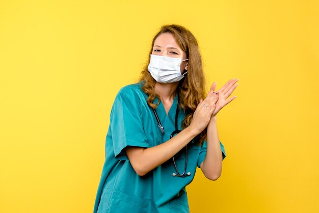 Front view of female doctor in mask on yellow wall