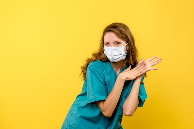 Front view of female doctor in mask on yellow wall