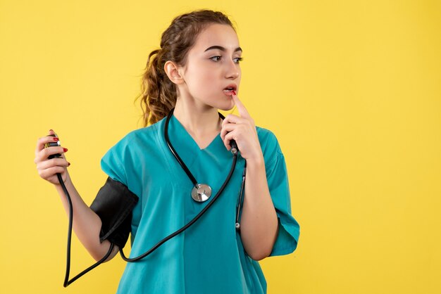 Front view female doctor in medical shirt checking her pressure, virus health emotion covid-19 pandemic