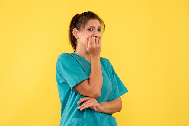 Front view female doctor in medical shirt scared on yellow background