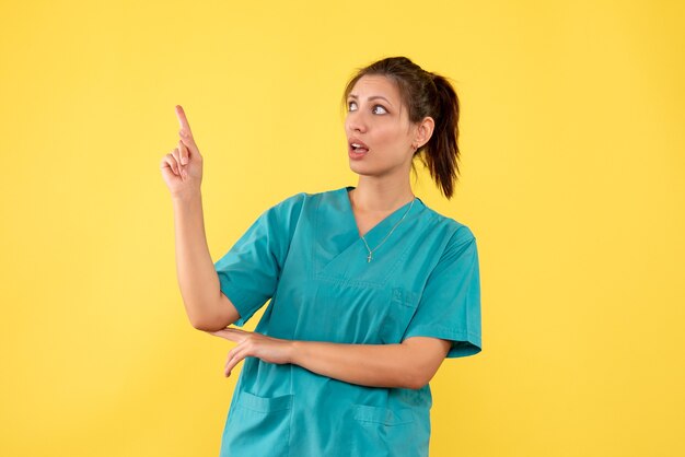 Front view female doctor in medical shirt on a yellow background