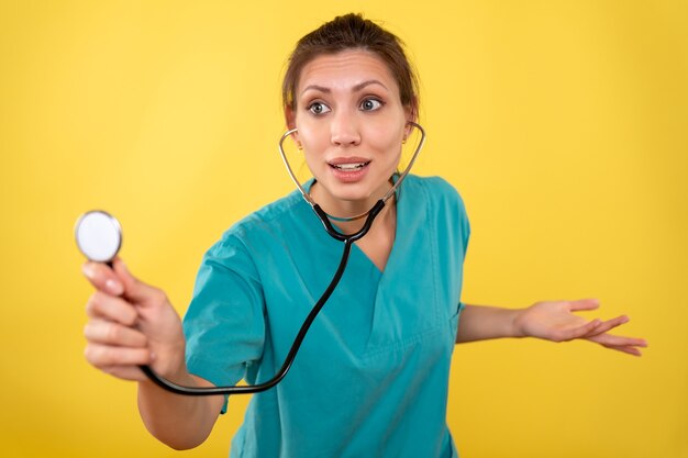 Front view female doctor in medical shirt on yellow background