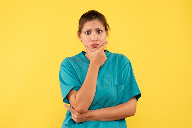 Front view female doctor in medical shirt on yellow background