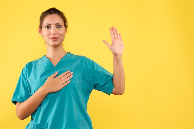 Front view female doctor in medical shirt on yellow background