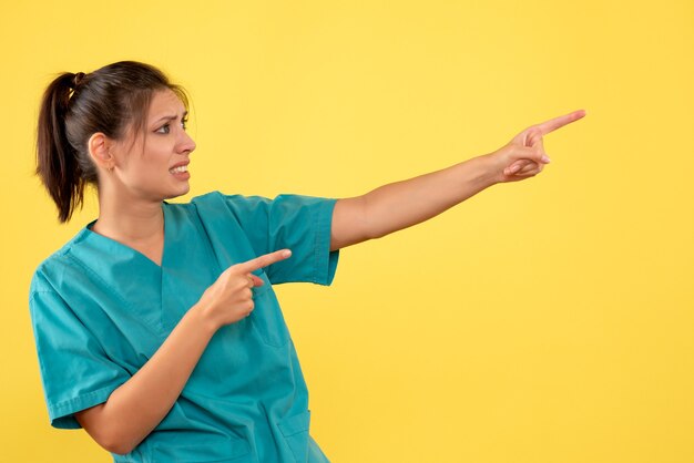 Front view female doctor in medical shirt on yellow background