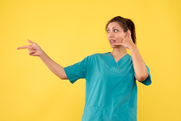 Front view female doctor in medical shirt on yellow background