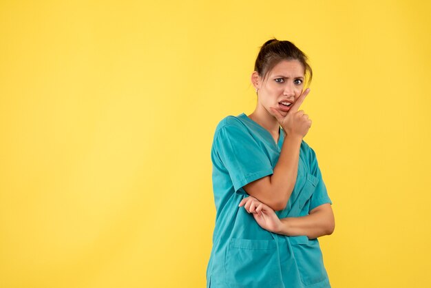 Front view female doctor in medical shirt on yellow background