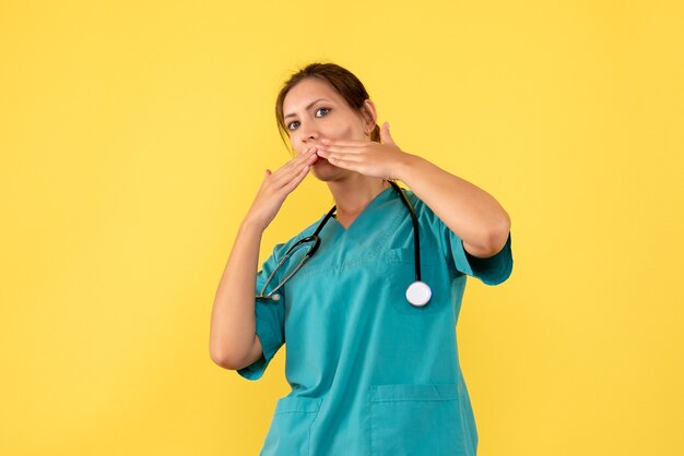 Front view female doctor in medical shirt on yellow background