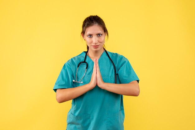 Front view female doctor in medical shirt on yellow background