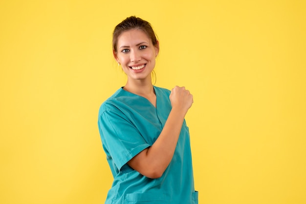 Front view female doctor in medical shirt on yellow background