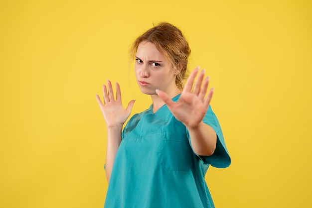 Front view female doctor in medical shirt on yellow desk hospital medic covid-19 nurse health medicine color