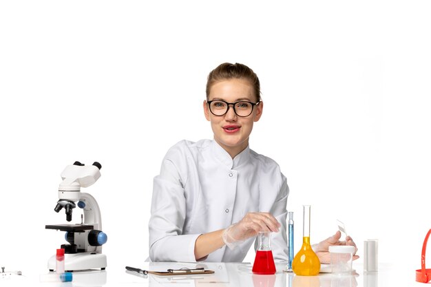 Front view female doctor in medical suit with gloves in working process on the white space