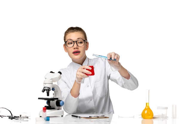 Free Photo front view female doctor in medical suit with gloves working with solutions on the white space