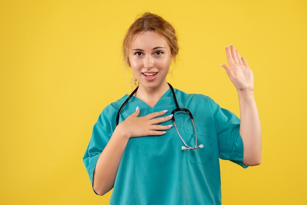 Free photo front view of female doctor in medical suit with stethoscope on yellow wall