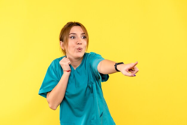 Front view female doctor pointing on yellow space