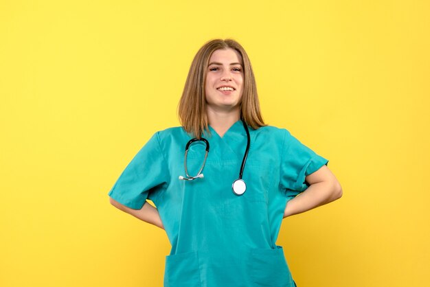 Front view female doctor posing and smiling on yellow space