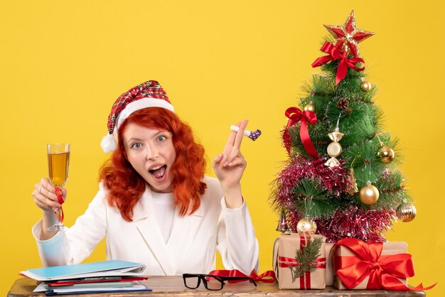 Front view female doctor sitting and celebrating christmas with champagne