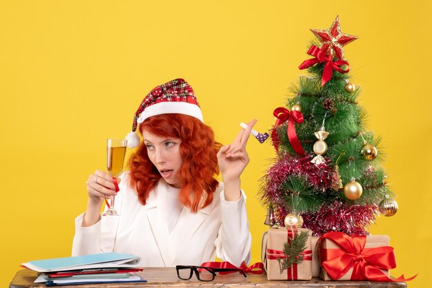 Front view female doctor sitting and celebrating christmas with champagne