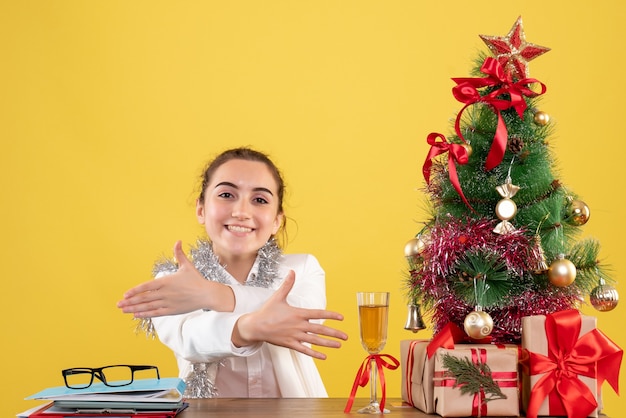 Free photo front view female doctor sitting behind her table on yellow background