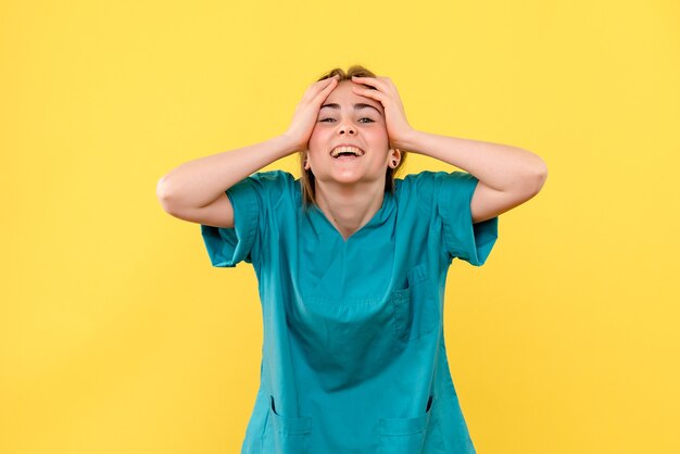 Front view female doctor smiling on yellow background medic emotion hospital health