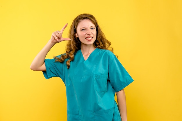 Front view of female doctor smiling on yellow wall