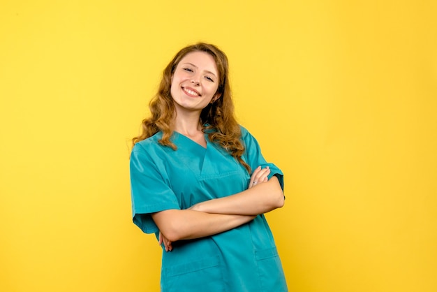 Front view of female doctor smiling on yellow wall