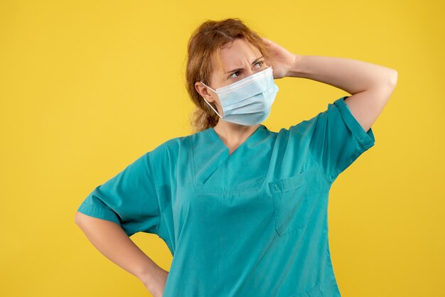 Front view of female doctor in sterile protective mask on yellow wall