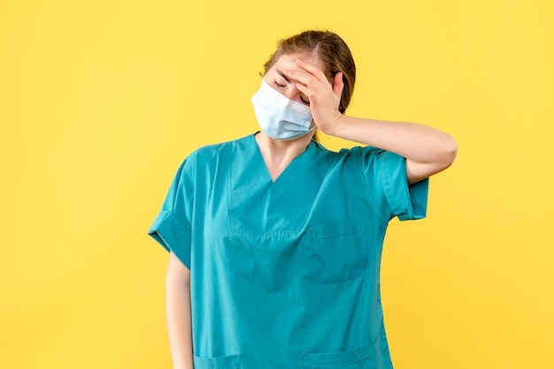 Front view female doctor stressed in mask on yellow background health hospital covid pandemic