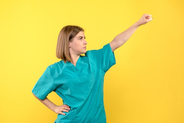 Front view female doctor in superman pose on yellow space