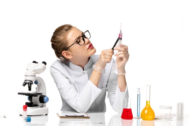 Front view female doctor in white medical suit holding injection on light-white space